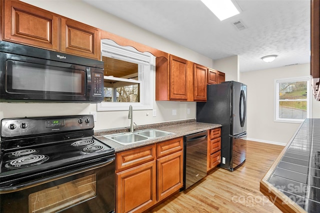 kitchen with sink, black appliances, a textured ceiling, and light hardwood / wood-style flooring