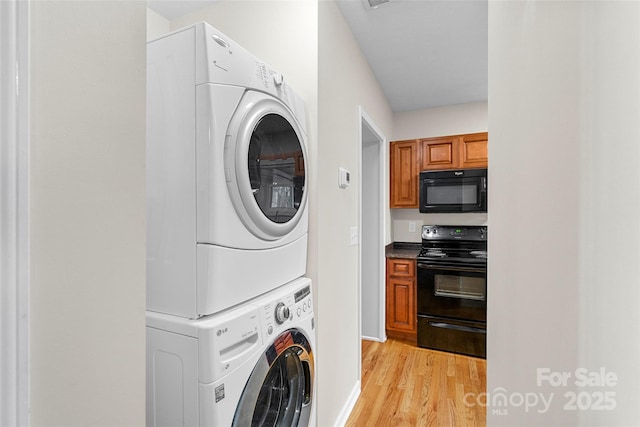 laundry room with light hardwood / wood-style floors and stacked washer / dryer