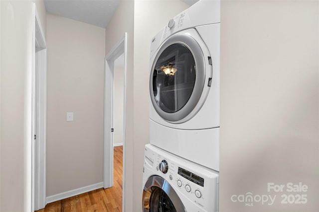 laundry room with stacked washing maching and dryer and light hardwood / wood-style floors