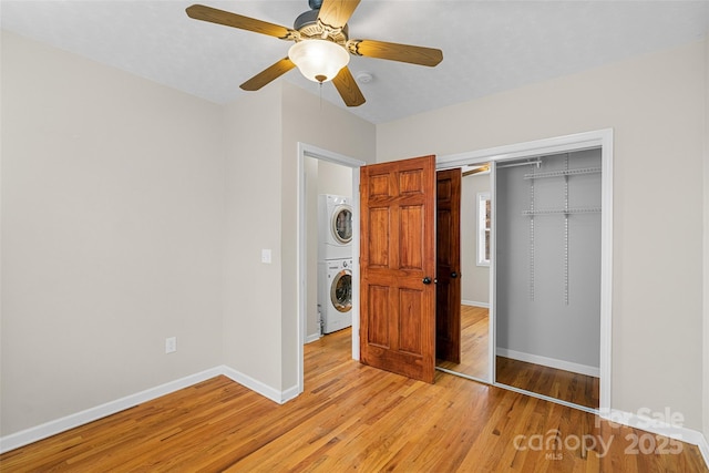 unfurnished bedroom with a closet, ceiling fan, stacked washer and dryer, and light hardwood / wood-style flooring