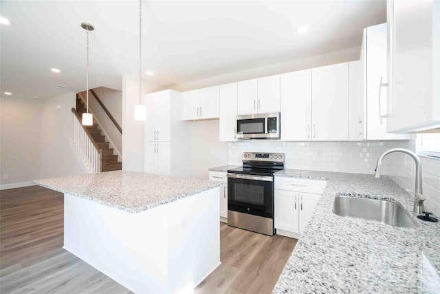 kitchen with white cabinetry, sink, decorative light fixtures, and appliances with stainless steel finishes