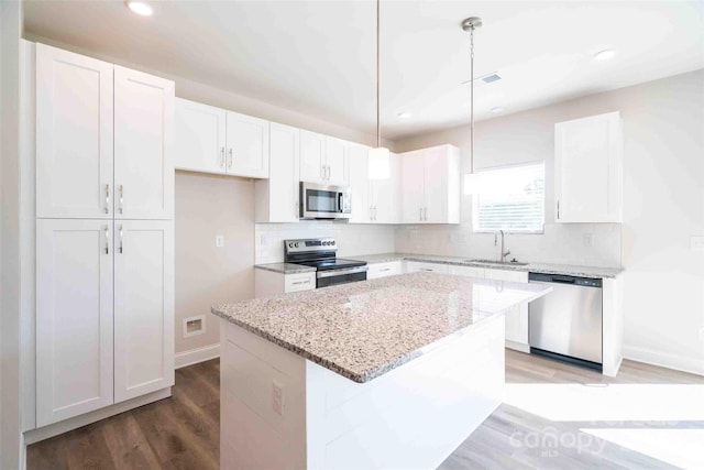 kitchen featuring light stone countertops, a center island, white cabinets, and appliances with stainless steel finishes