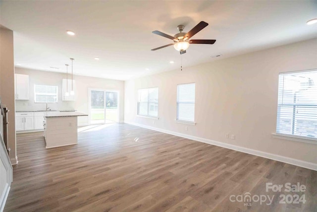 unfurnished living room with a wealth of natural light, sink, ceiling fan, and dark hardwood / wood-style floors