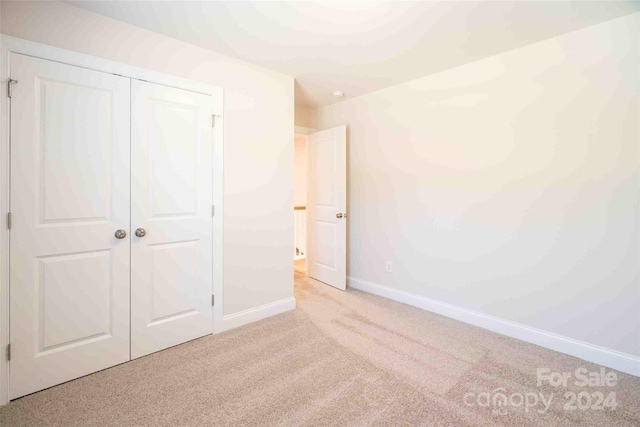 unfurnished bedroom with light carpet and a closet