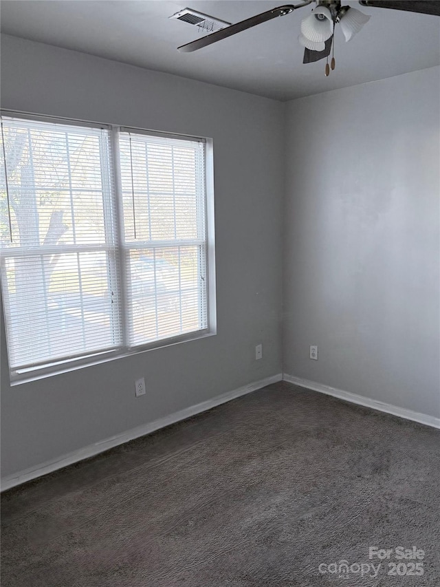 spare room with dark carpet, plenty of natural light, and ceiling fan