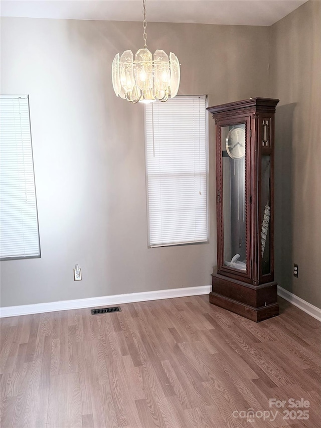 unfurnished dining area featuring a notable chandelier and hardwood / wood-style flooring