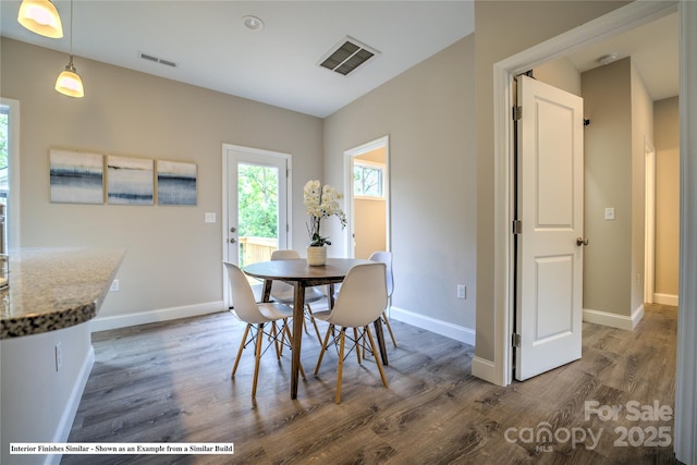 dining room with wood finished floors, visible vents, and baseboards