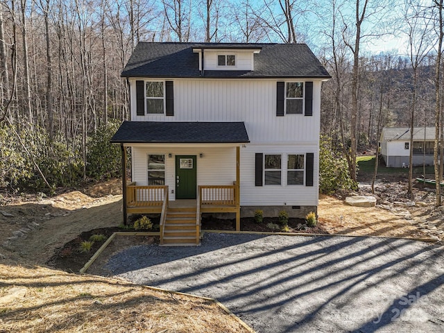 view of front of house featuring crawl space, a wooded view, a porch, and a shingled roof