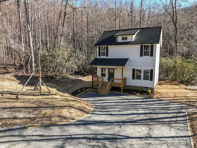 view of front facade with crawl space, covered porch, and a wooded view