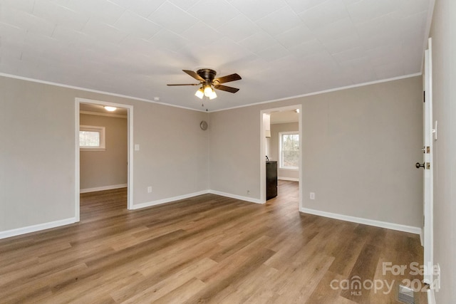 unfurnished room with wood-type flooring, crown molding, ceiling fan, and a healthy amount of sunlight