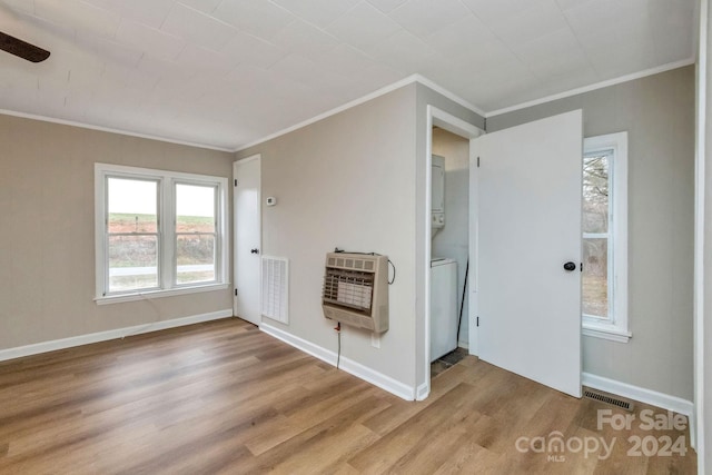 interior space featuring heating unit, hardwood / wood-style floors, stacked washing maching and dryer, and ornamental molding