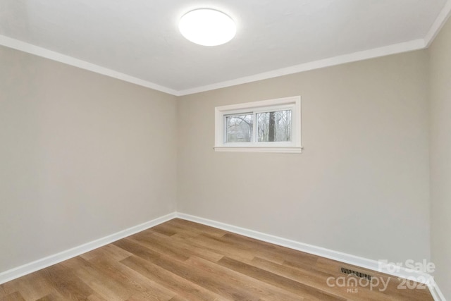 spare room featuring hardwood / wood-style flooring and crown molding