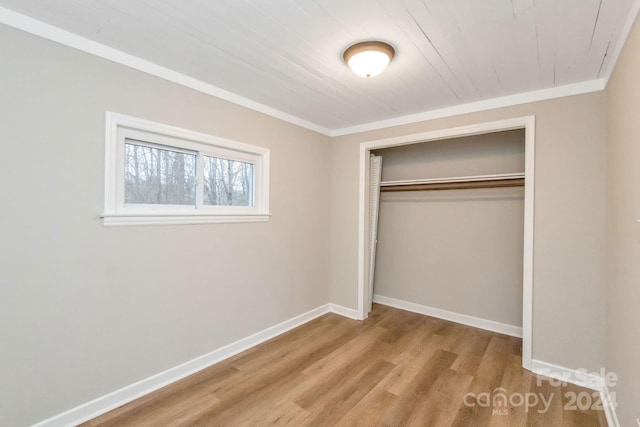 unfurnished bedroom featuring crown molding, a closet, and light hardwood / wood-style flooring