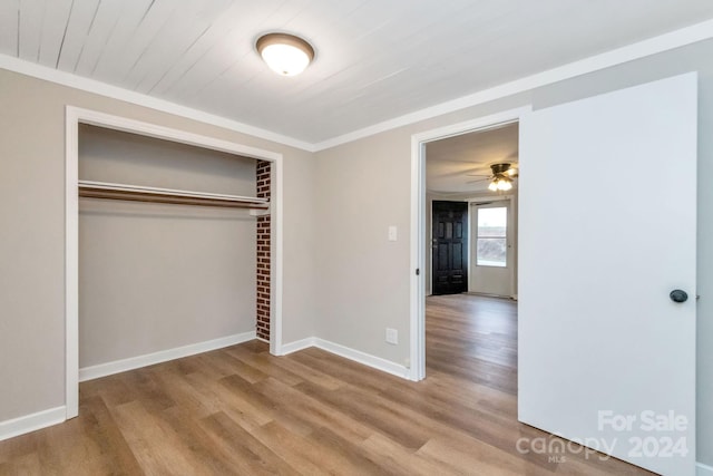 unfurnished bedroom with crown molding, a closet, and light wood-type flooring