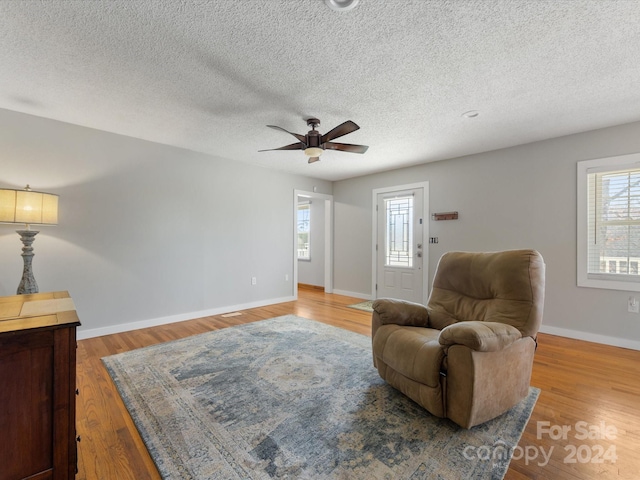 sitting room featuring ceiling fan, light hardwood / wood-style floors, and a textured ceiling