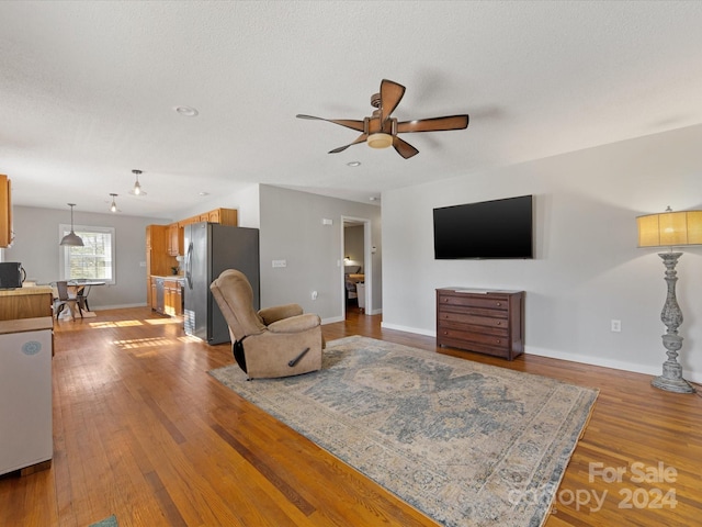 living room featuring ceiling fan, a textured ceiling, and light hardwood / wood-style flooring