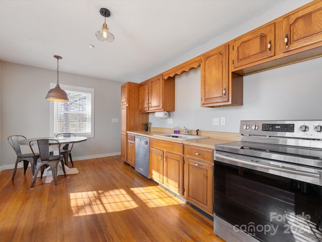 kitchen featuring light hardwood / wood-style floors, sink, stainless steel appliances, and hanging light fixtures