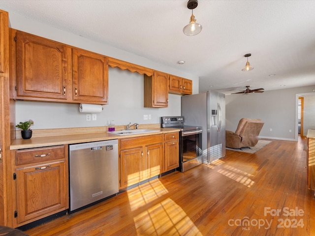 kitchen with hardwood / wood-style flooring, sink, hanging light fixtures, and appliances with stainless steel finishes