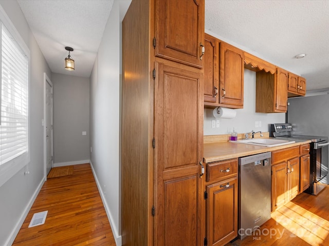 kitchen with sink, stainless steel appliances, a textured ceiling, and light wood-type flooring