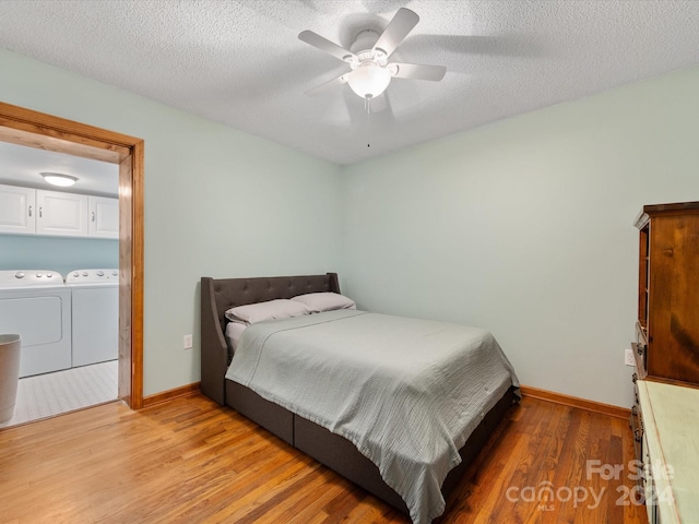 bedroom with hardwood / wood-style floors, a textured ceiling, ceiling fan, and washing machine and clothes dryer