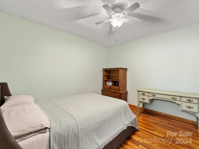 bedroom with ceiling fan, a textured ceiling, and hardwood / wood-style flooring