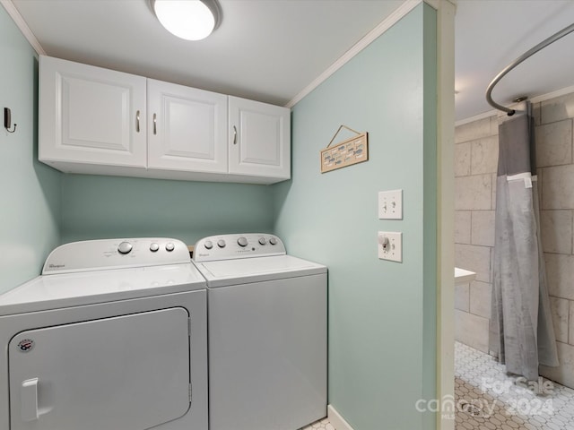 clothes washing area with cabinets, washing machine and dryer, ornamental molding, and light tile patterned floors