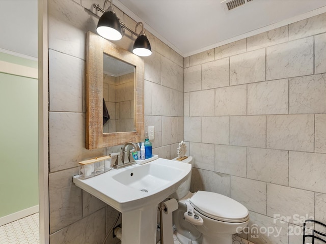 bathroom with toilet, tile walls, and ornamental molding