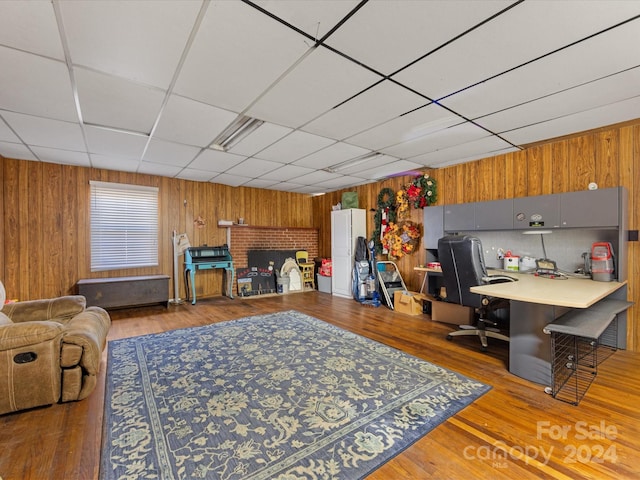 living room featuring a paneled ceiling, wood walls, and hardwood / wood-style floors