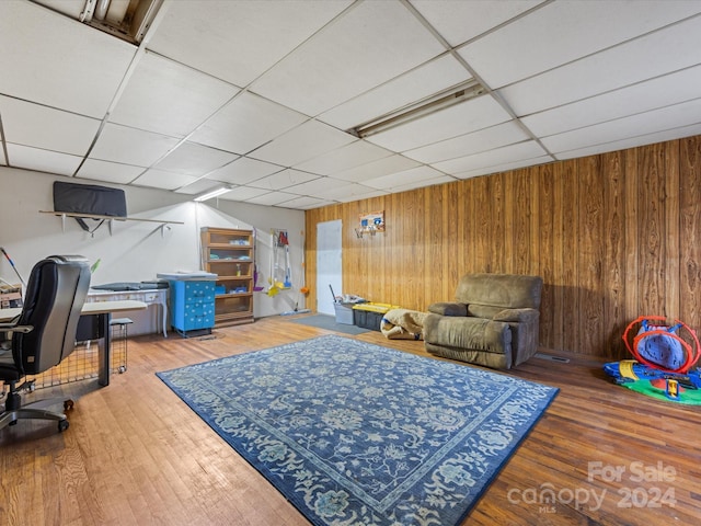 office with a paneled ceiling, wooden walls, and hardwood / wood-style flooring