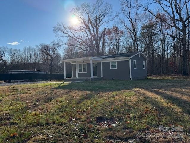 back of property with a lawn and a porch