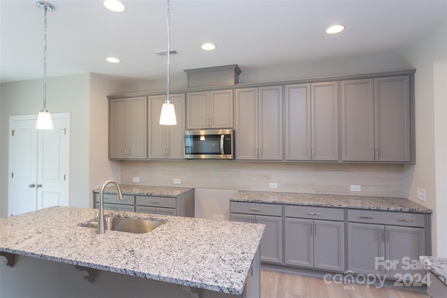 kitchen with gray cabinetry, decorative light fixtures, sink, and tasteful backsplash