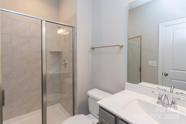 bathroom featuring vanity, toilet, and a shower with door