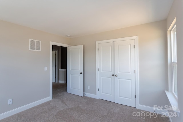 unfurnished bedroom with light carpet and a closet