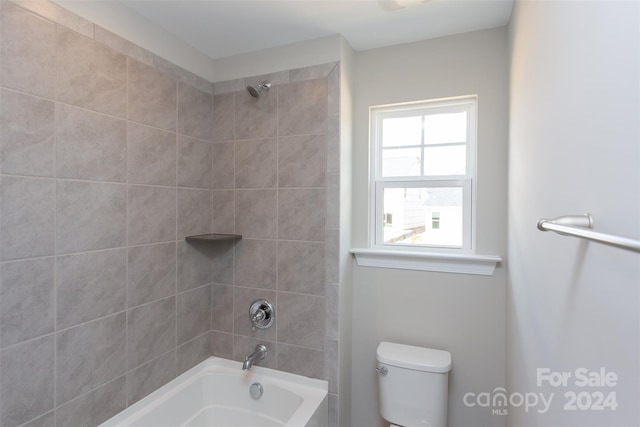 bathroom with tiled shower / bath combo and toilet