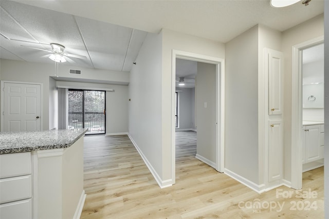 kitchen featuring a textured ceiling, white cabinetry, light hardwood / wood-style flooring, and ceiling fan