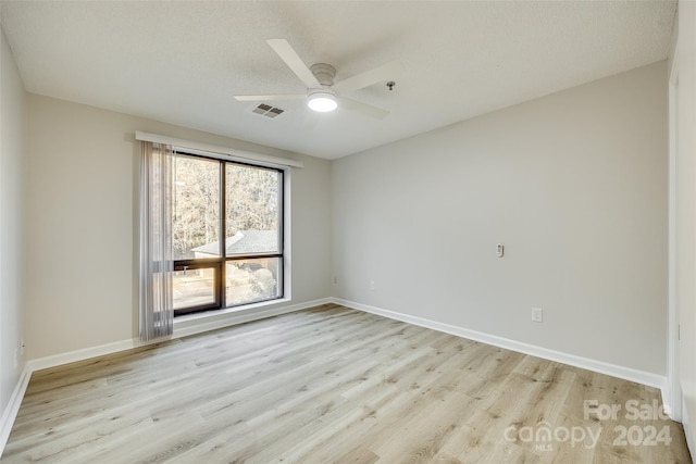 unfurnished room with ceiling fan, light wood-type flooring, and a textured ceiling