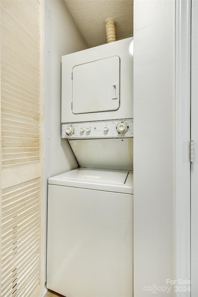 laundry area featuring stacked washing maching and dryer and a textured ceiling