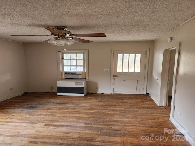 interior space with a textured ceiling, light wood-type flooring, plenty of natural light, and cooling unit