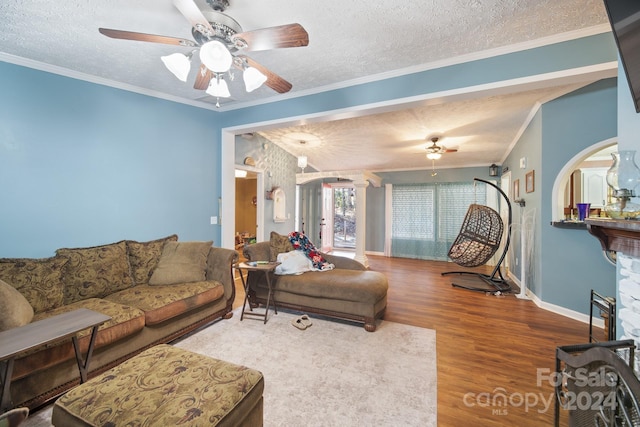 living room featuring wood-type flooring, a textured ceiling, ceiling fan, and crown molding