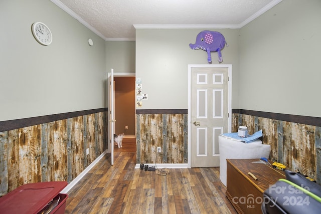 sitting room with a textured ceiling, dark hardwood / wood-style floors, crown molding, and wood walls