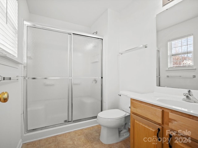 bathroom featuring tile patterned floors, toilet, vanity, and walk in shower