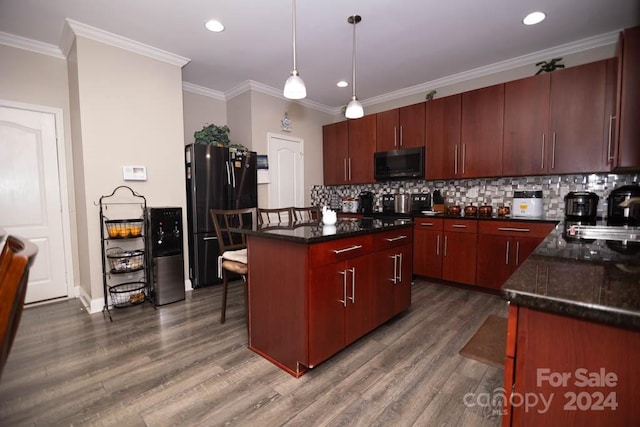 kitchen with pendant lighting, a center island, black refrigerator, sink, and dark stone countertops