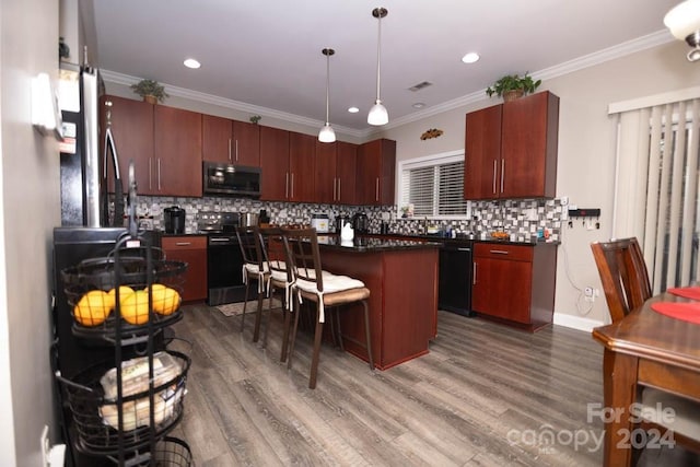 kitchen with tasteful backsplash, wood-type flooring, a kitchen bar, a kitchen island, and appliances with stainless steel finishes