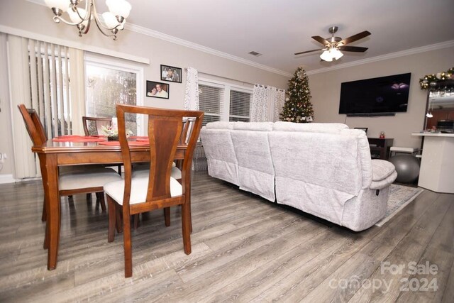 dining space with wood-type flooring, ceiling fan with notable chandelier, and ornamental molding