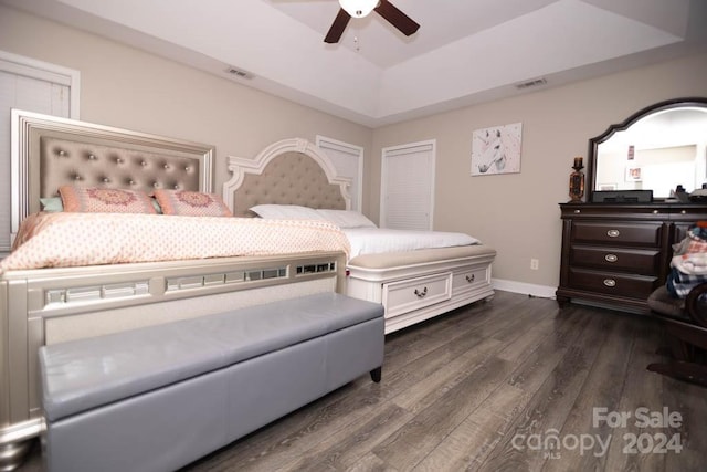 bedroom featuring ceiling fan, a raised ceiling, and dark wood-type flooring