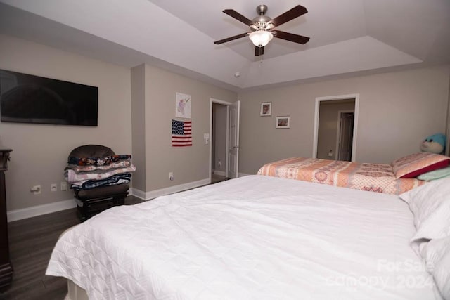 bedroom featuring ceiling fan, dark hardwood / wood-style flooring, and a tray ceiling