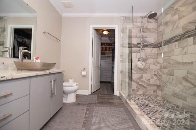 bathroom featuring crown molding, toilet, vanity, and tiled shower