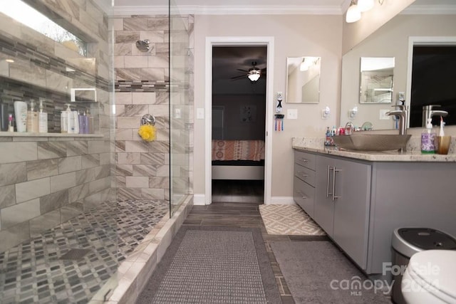 bathroom featuring ceiling fan, crown molding, vanity, and tiled shower