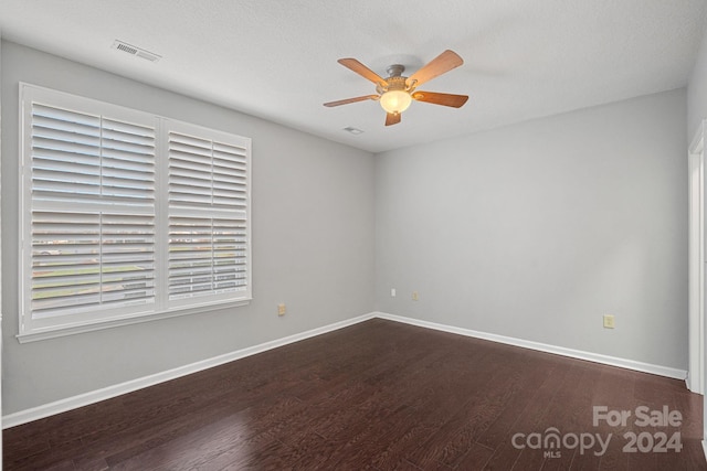 empty room with a textured ceiling, ceiling fan, and dark hardwood / wood-style floors