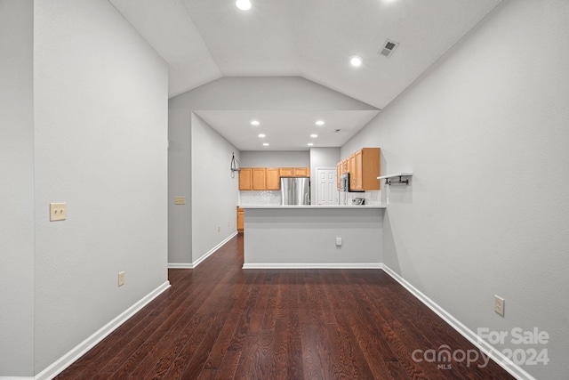 kitchen with kitchen peninsula, dark wood-type flooring, stainless steel refrigerator, and lofted ceiling